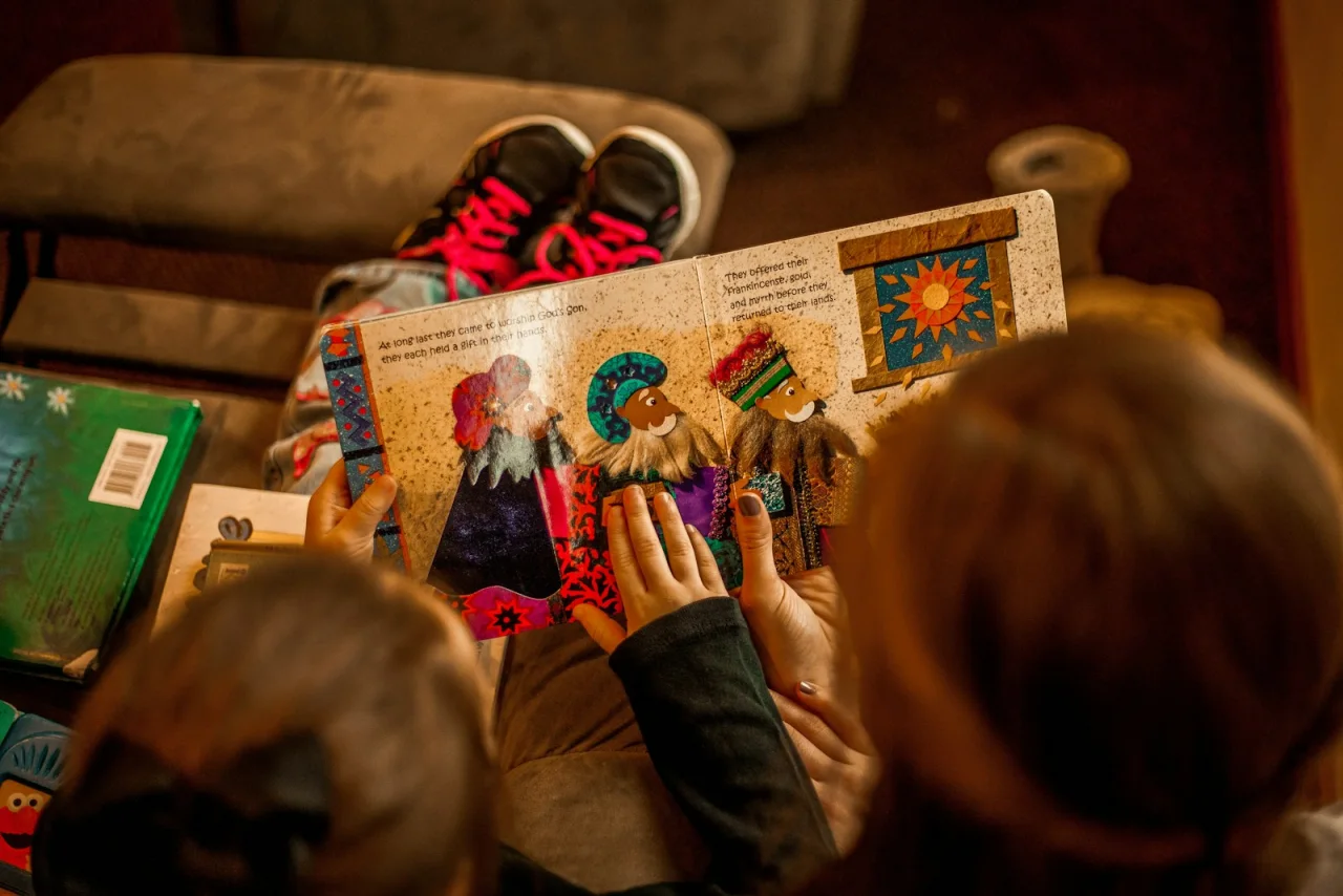 Two children reading an open, colorful illustrated picture book together