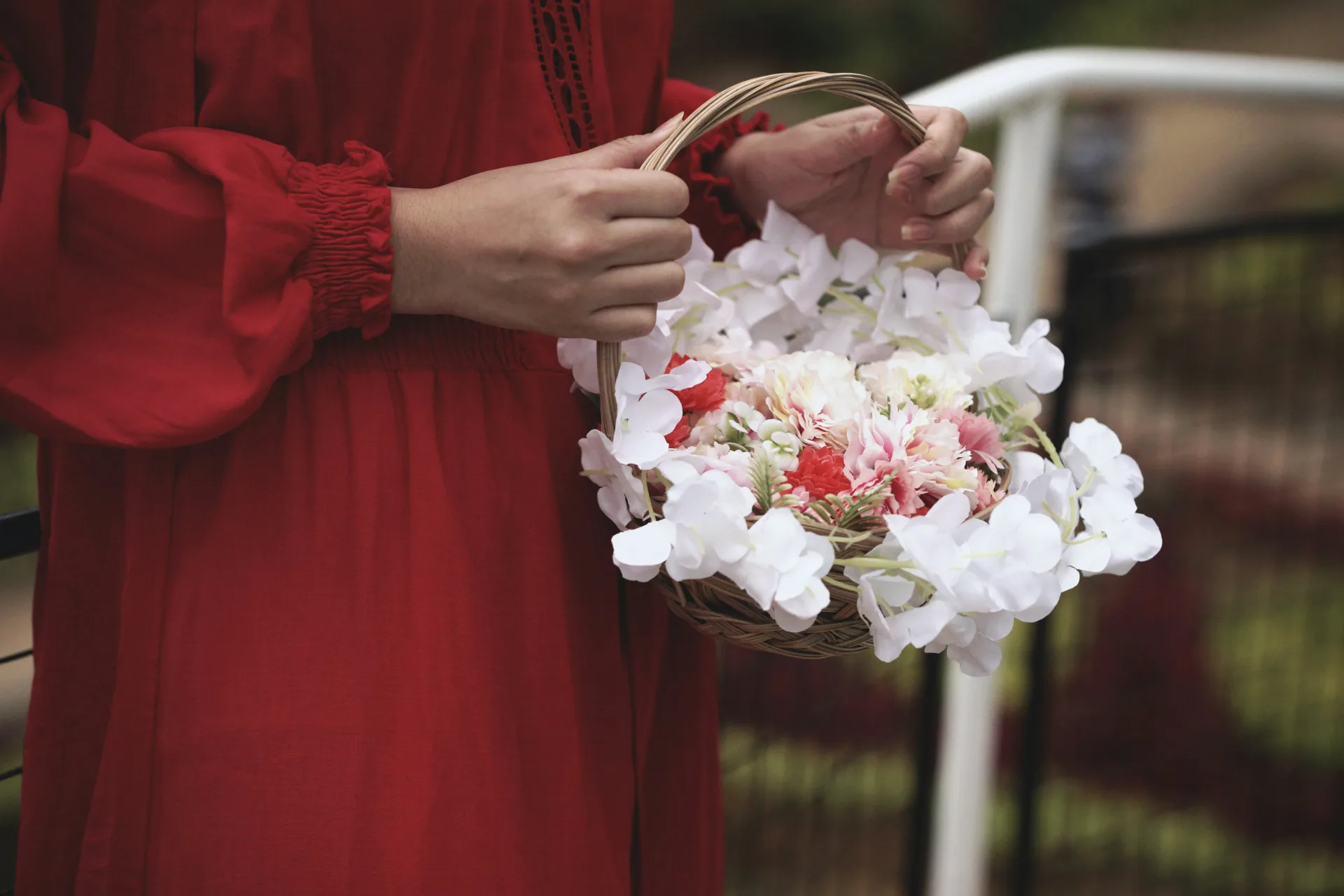 Close-up of hands, no faces, holding open a printed storybook that shows a child's crayon flower girl scattering petals, laid on a lace wedding table beside real rose petals