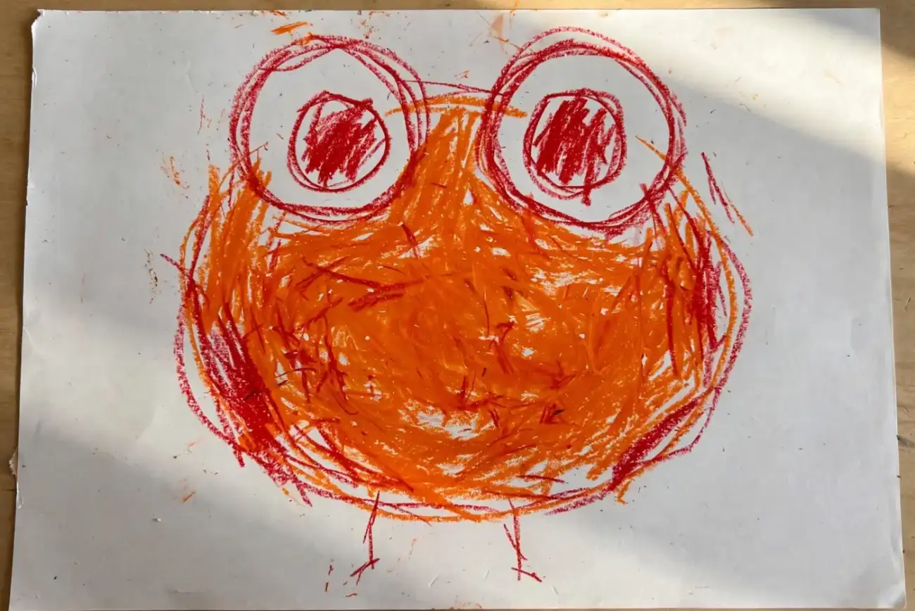 A child's heavy orange and red crayon drawing of a round creature with an enormous body, two oversized circle eyes and two tiny stick legs