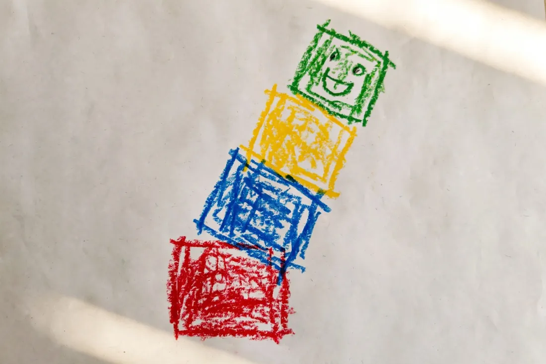 Billie's chunky crayon drawing of a leaning tower of four colored blocks with a face on the top one, used as the hero of her DoodleTale storybook